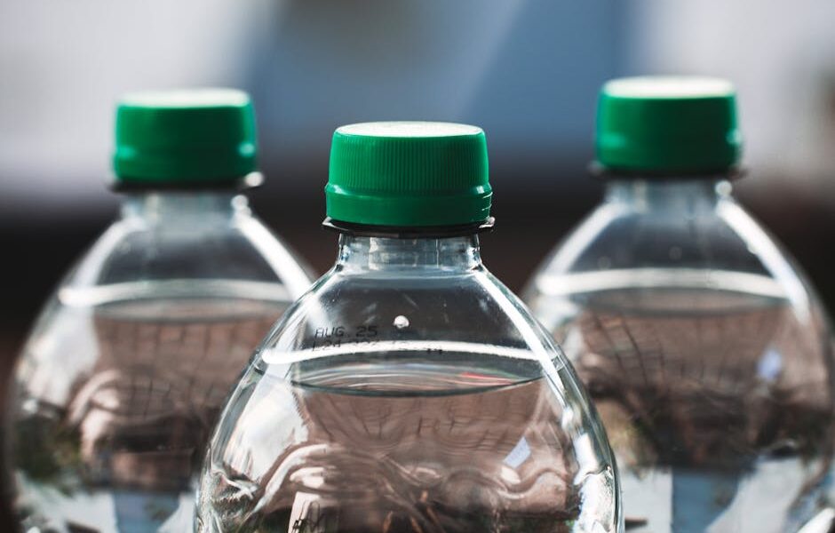 Focused view of three clear plastic bottles with green caps outdoors.